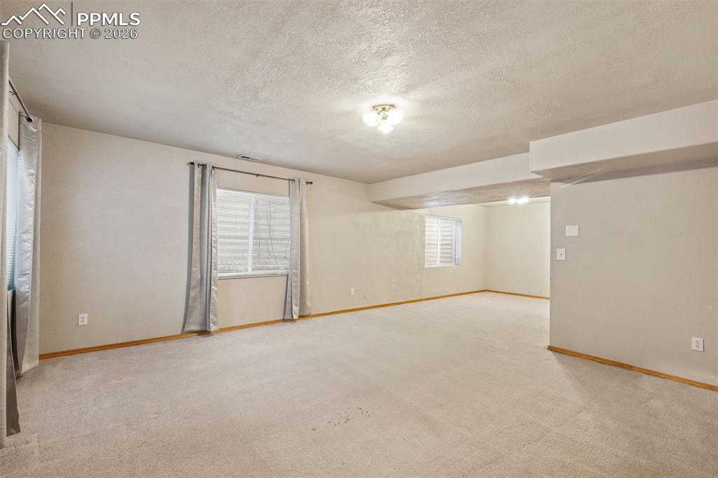 Image 33 of 40: Carpeted interior space featuring neutral wall tones, wood-finish baseboard