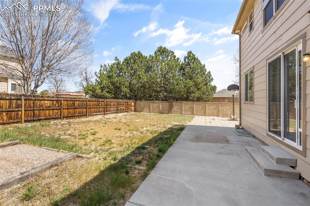 Image 37 of 40: Spacious backyard featuring a concrete patio, sliding glass door, wood priv