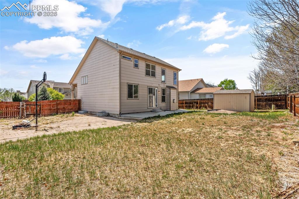 Image 39 of 40: Expansive backyard featuring a large patio, a storage shed, and perimeter f