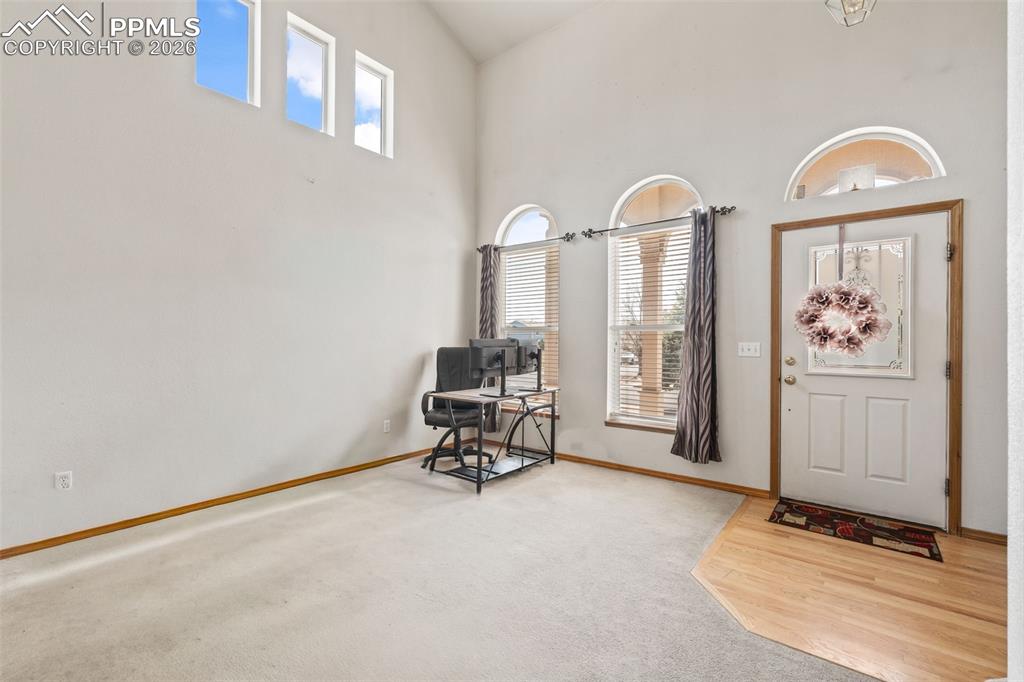 Image 7 of 40: Foyer featuring soaring ceilings, a white entry door with a decorative wind