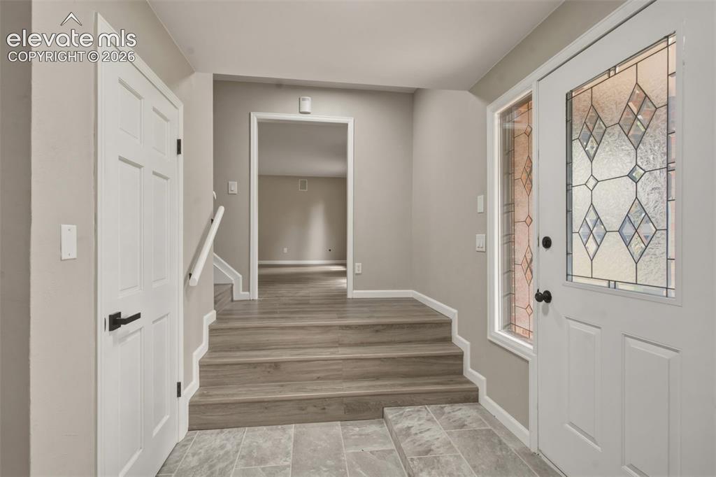 Image 11 of 32: Entryway featuring a white paneled door with decorative glass, tile floorin