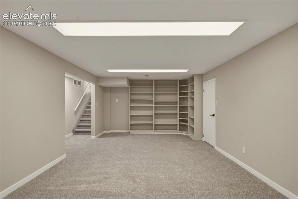 Image 12 of 32: Recessed ceiling lighting, built-in shelving, gray carpeting, neutral wall 