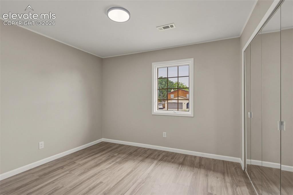 Image 14 of 32: Bright, light-filled bedroom showcasing wood-finish flooring, neutral wall