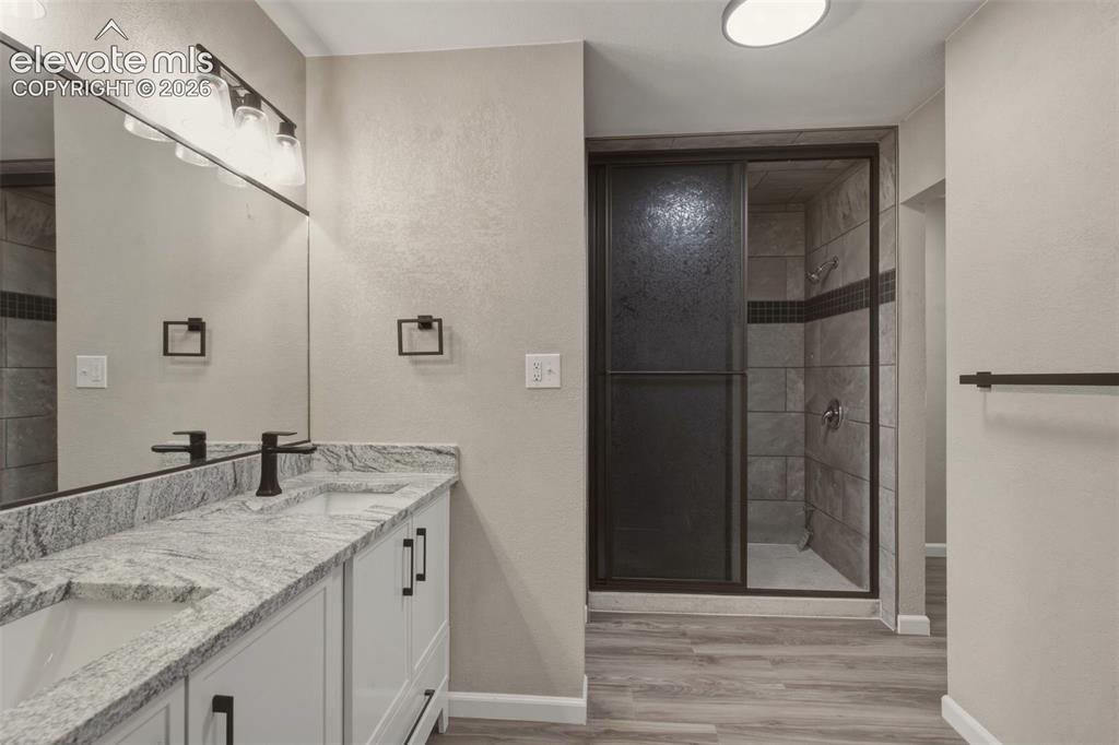Image 16 of 32: Dual vanity with granite countertop, white cabinetry, matte black fixtures,
