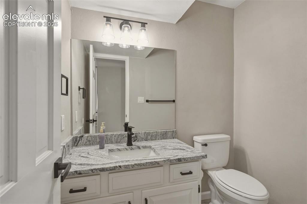 Image 17 of 32: Vanity with stone-finish countertop, undermount sink, and matte black fauce
