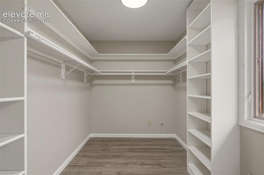Image 22 of 32: Spacious walk-in closet featuring dual hanging rods, extensive shelving alo