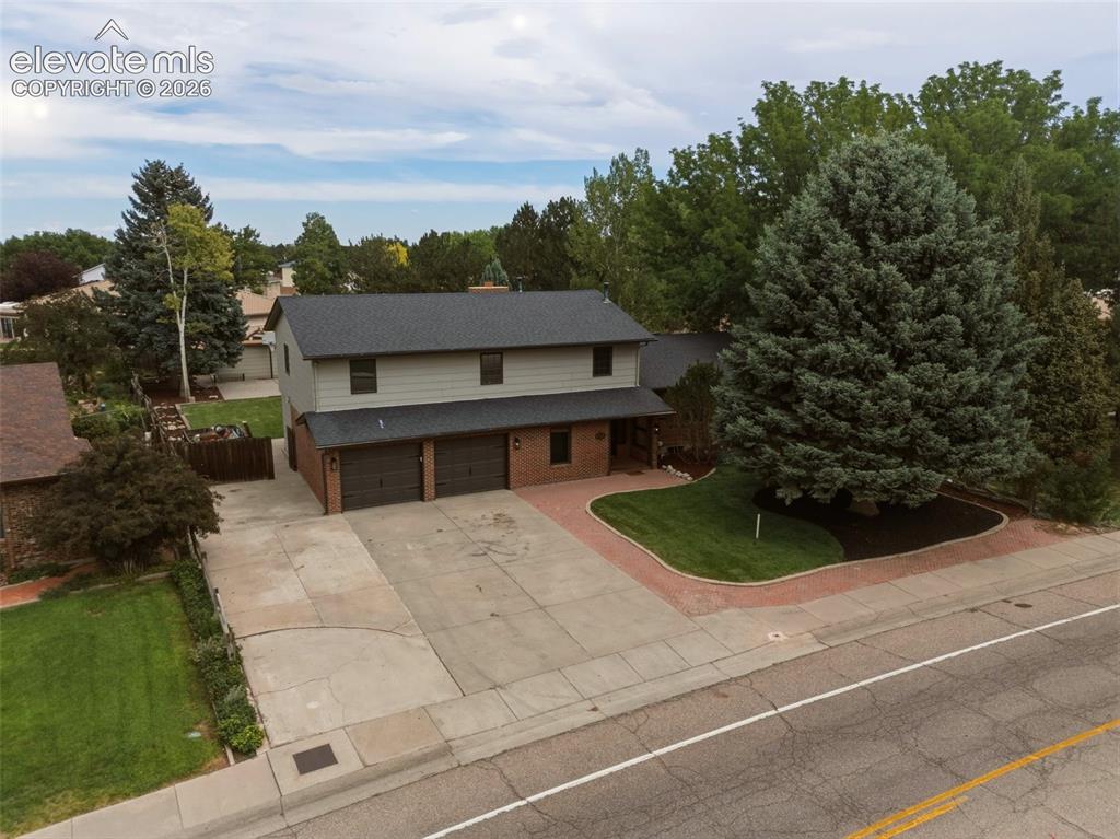Image 23 of 32: Two-story residence featuring a two-car garage, brick accents, and mature t
