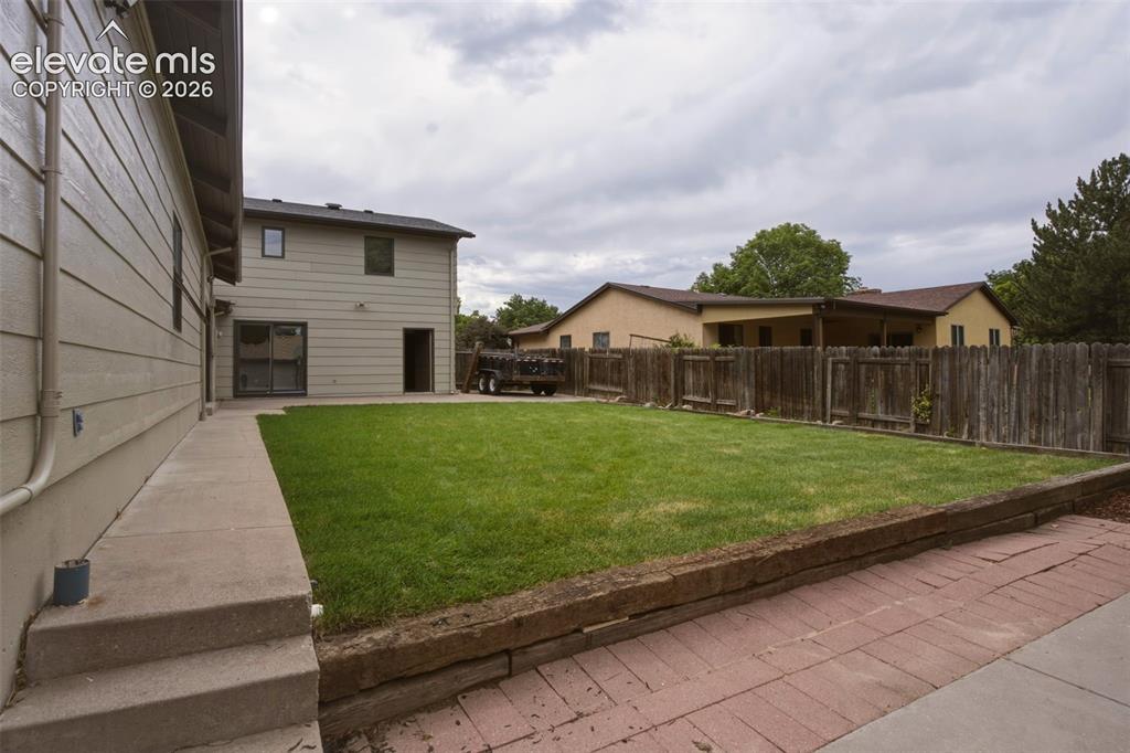 Image 27 of 32: Expansive lawn area with a wood fence perimeter