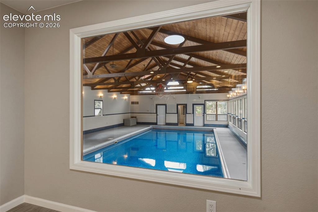 Image 4 of 32: Indoor swimming pool with exposed wood beam ceiling, skylights, extensive w