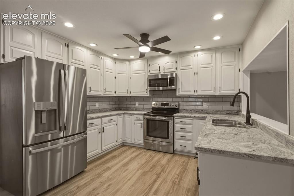Image 7 of 32: White cabinetry with dark hardware, stainless steel appliances, light wood-