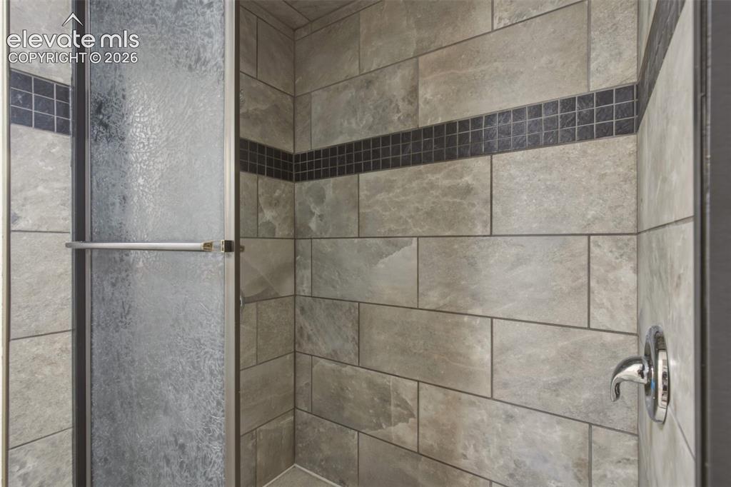 Image 9 of 32: Walk-in shower with textured glass enclosure, tiled walls, and decorative m