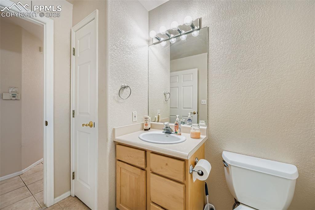 Image 10 of 11: Half bath with vanity, a textured wall, and light tile patterned floors