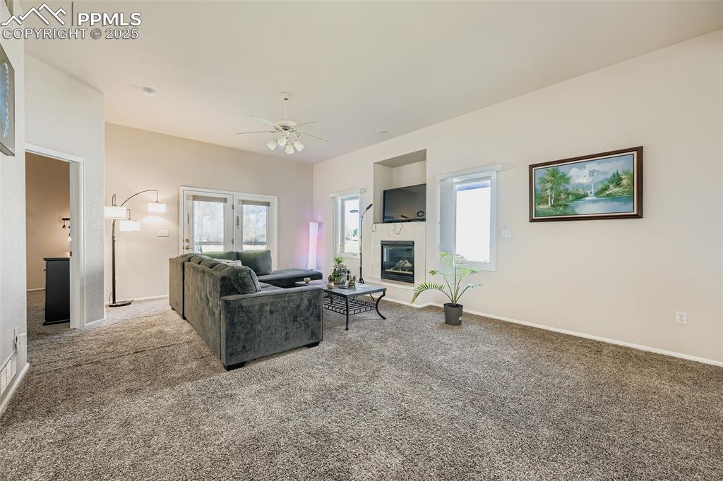 Image 3 of 11: Carpeted living room featuring ceiling fan and a glass covered fireplace