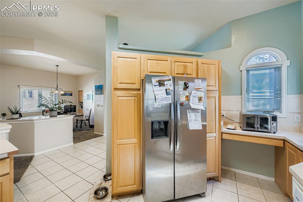 Image 6 of 11: Kitchen featuring stainless steel fridge, light countertops, light tile pat