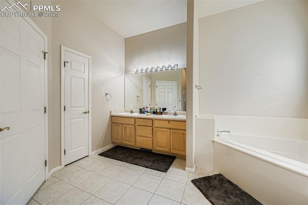 Image 8 of 11: Bathroom featuring double vanity, light tile patterned floors, and a garden