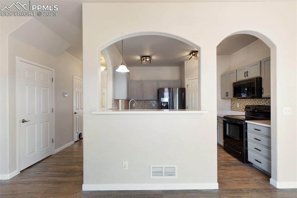 Image 17 of 42: Kitchen featuring electric range, gray cabinetry, arched walkways, stainles