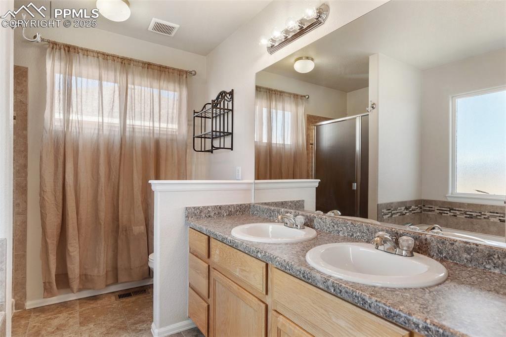 Image 22 of 42: Bathroom featuring double vanity, a stall shower, and a bath