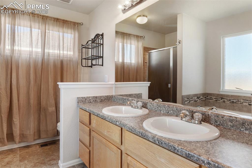 Image 23 of 42: Full bathroom featuring double vanity, a stall shower, and a garden tub