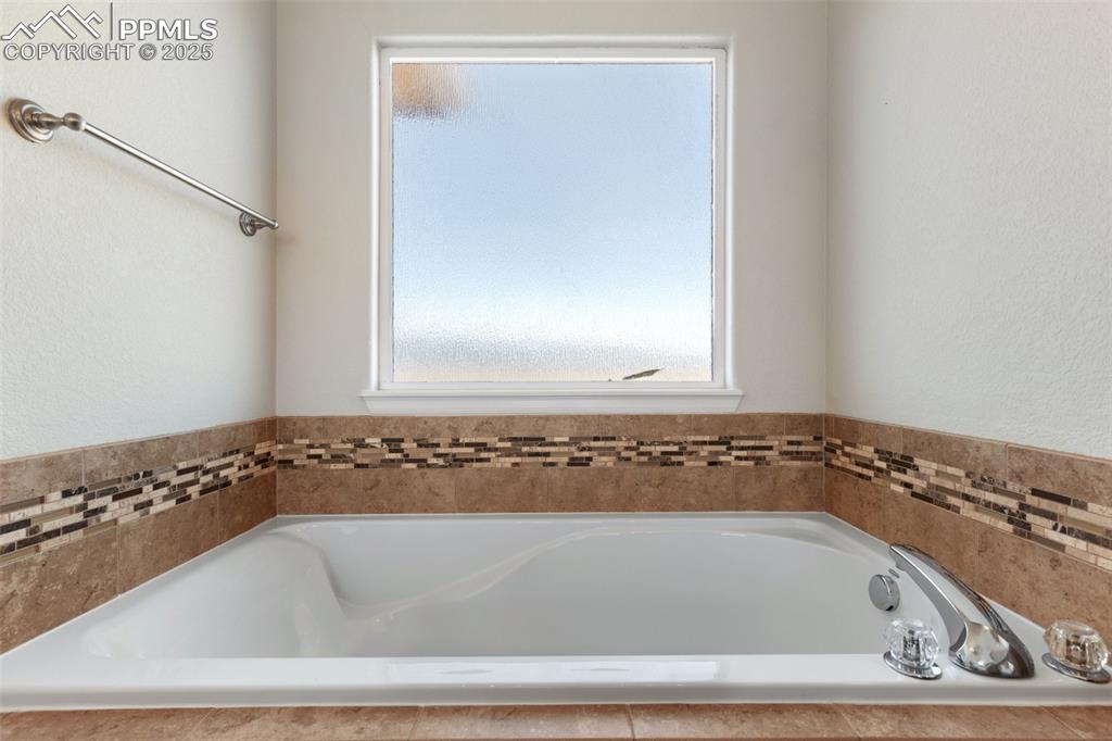 Image 25 of 42: Bathroom with a bath and a textured wall