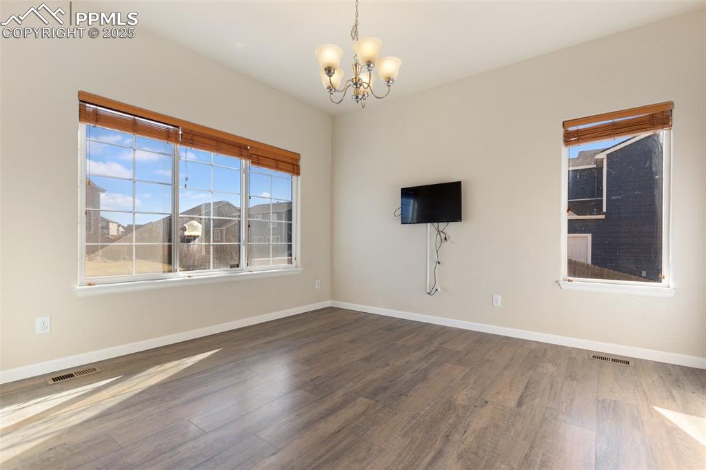 Image 26 of 42: Empty room featuring wood finished floors and a chandelier