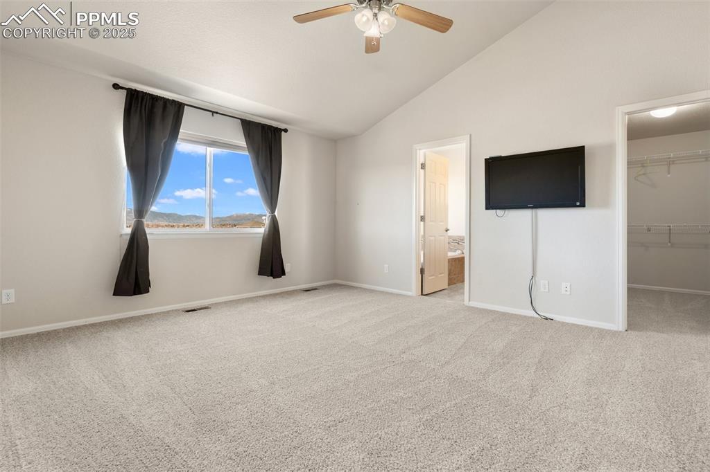 Image 29 of 42: Unfurnished bedroom with a spacious closet, carpet, ceiling fan, ensuite ba