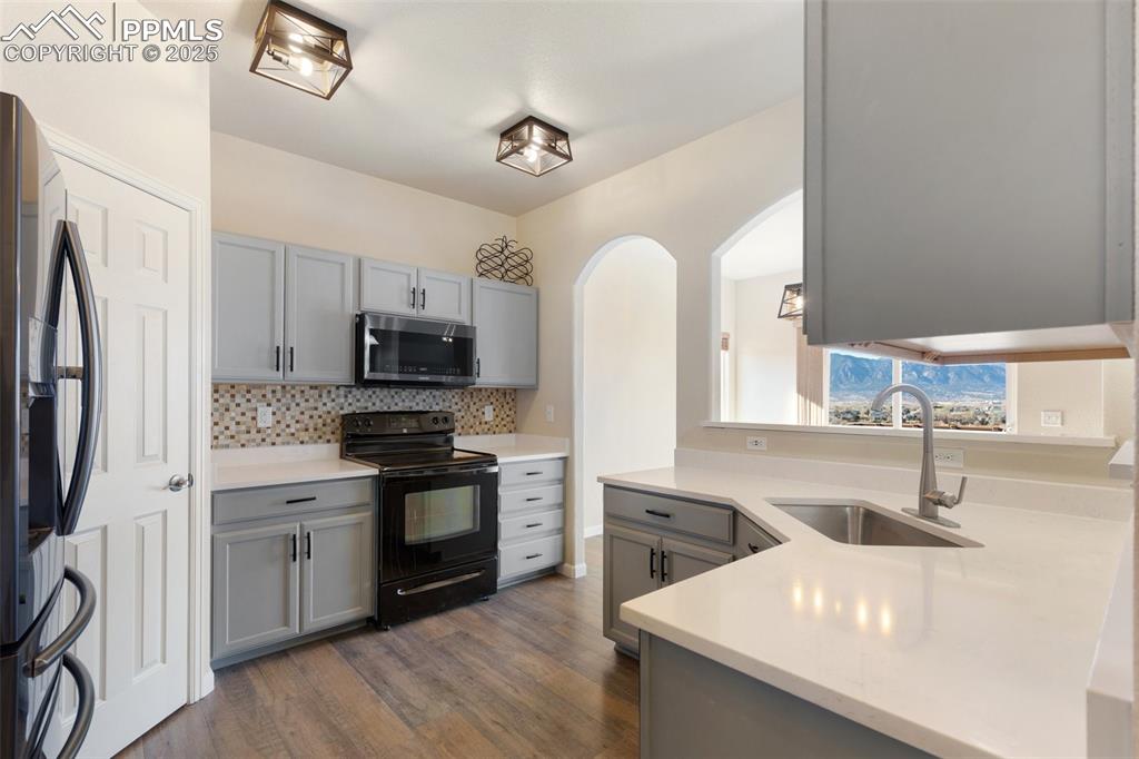 Image 3 of 42: Kitchen with gray cabinets, stainless steel appliances, dark wood finished 