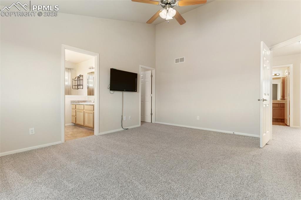 Image 30 of 42: Unfurnished bedroom featuring ensuite bath, light colored carpet, high vaul