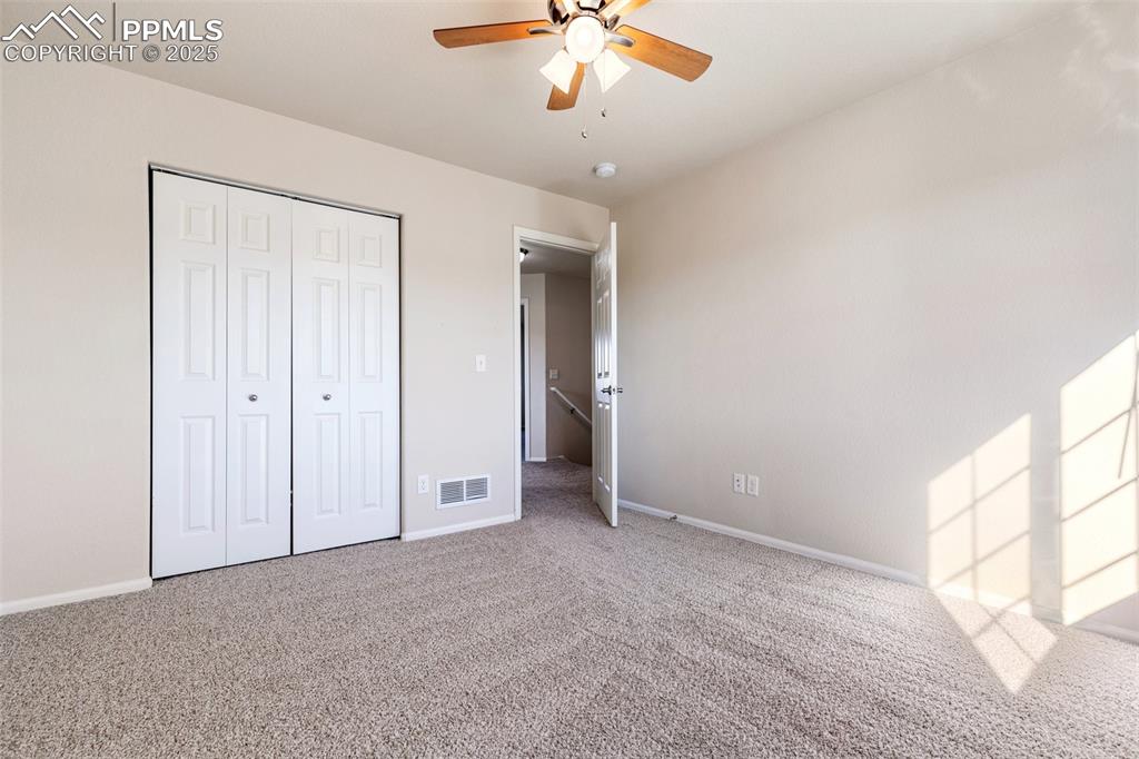 Image 34 of 42: Unfurnished bedroom with light colored carpet, a closet, and a ceiling fan