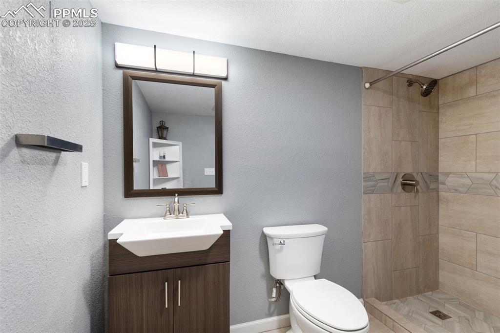 Image 35 of 42: Bathroom with a textured wall, vanity, and a stall shower