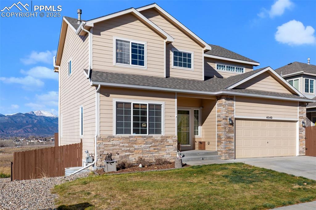 Image 6 of 42: View of front of house with a mountain view, stone siding, driveway, a gara