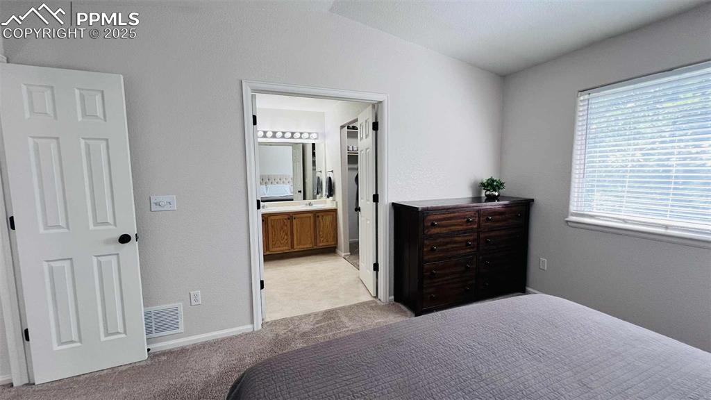 Image 13 of 35: Bedroom featuring a textured wall, light colored carpet, connected bathroom