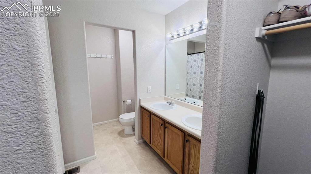 Image 16 of 35: Bathroom with double vanity and a textured wall