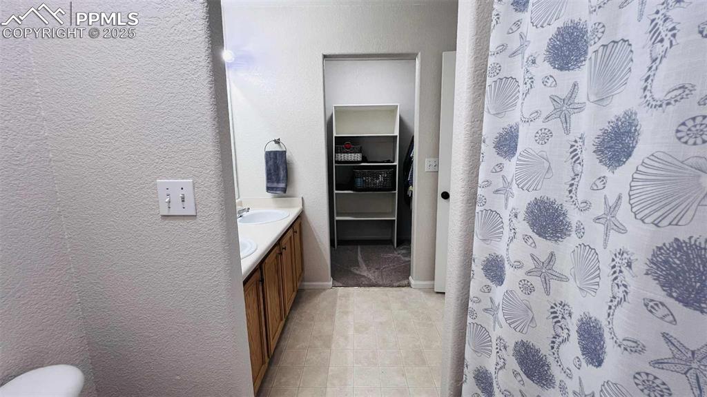 Image 18 of 35: Bathroom featuring vanity, a textured wall, and a shower with curtain