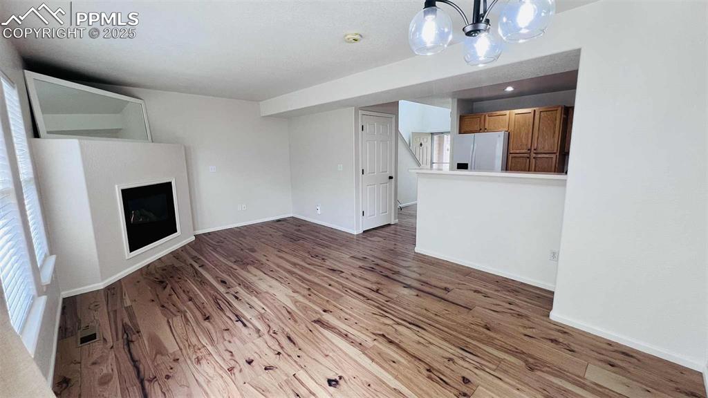Image 3 of 35: Unfurnished living room with wood finished floors and a chandelier