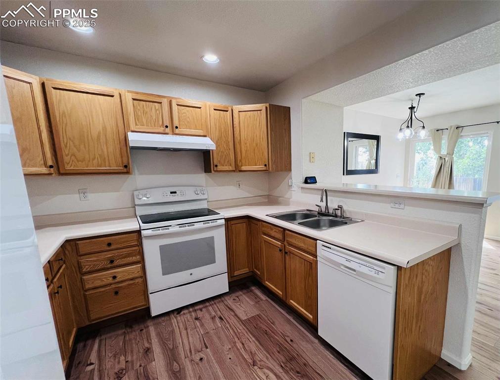 Image 6 of 35: Kitchen with white appliances, a peninsula, dark wood finished floors, unde