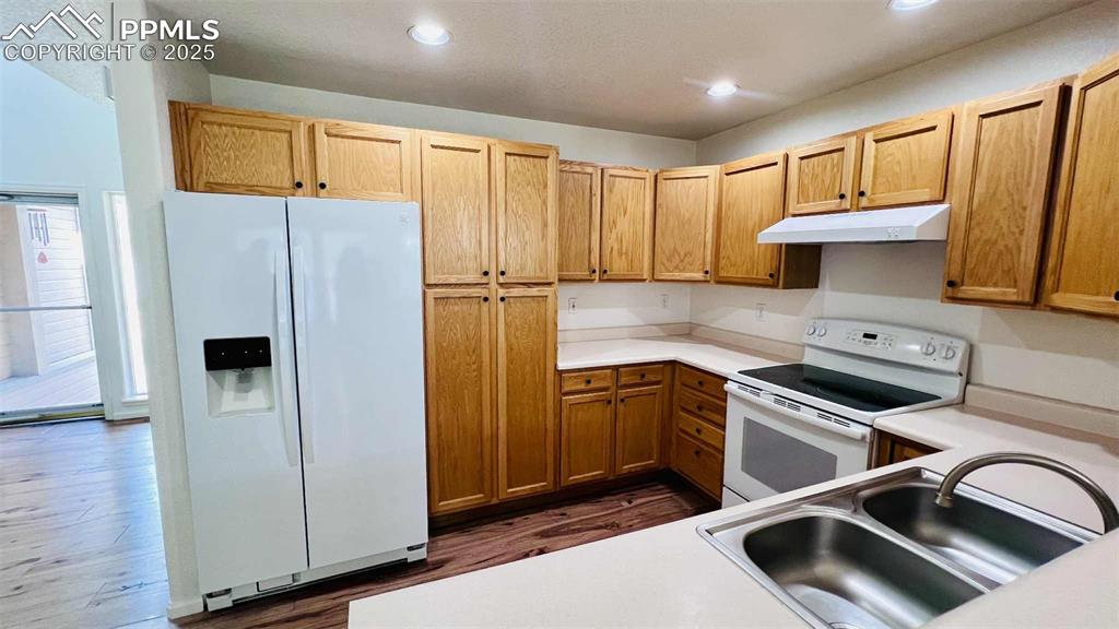 Image 7 of 35: Kitchen featuring white appliances, under cabinet range hood, light counter