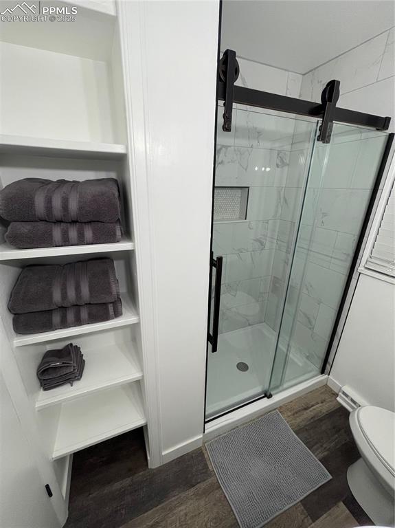 Image 3 of 12: Bathroom with a marble finish shower and wood finished floors