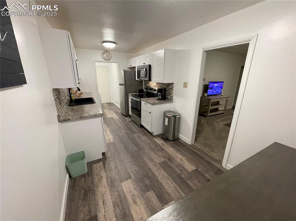 Image 5 of 12: Kitchen featuring backsplash, white cabinetry, stainless steel appliances,