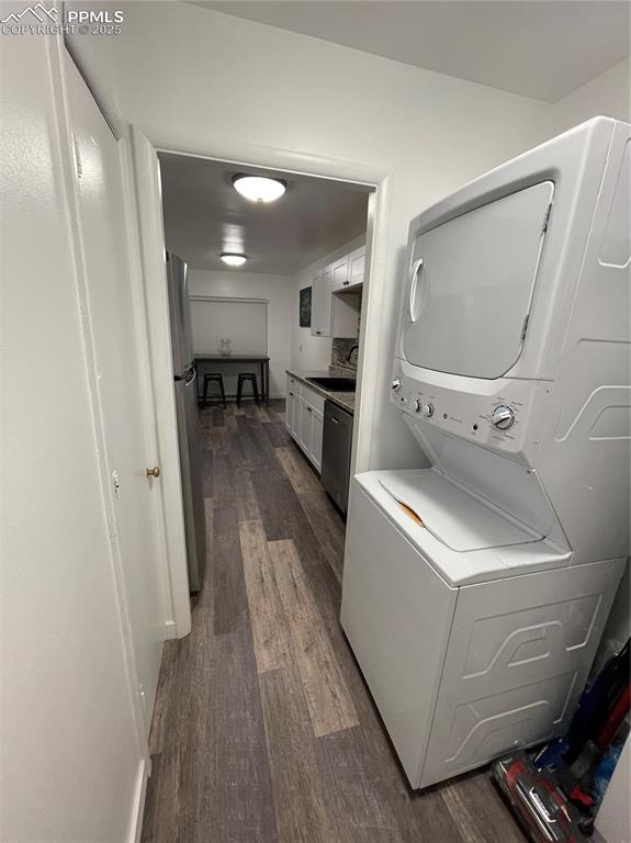 Image 6 of 12: Laundry area with stacked washing machine and dryer and dark wood-style flo