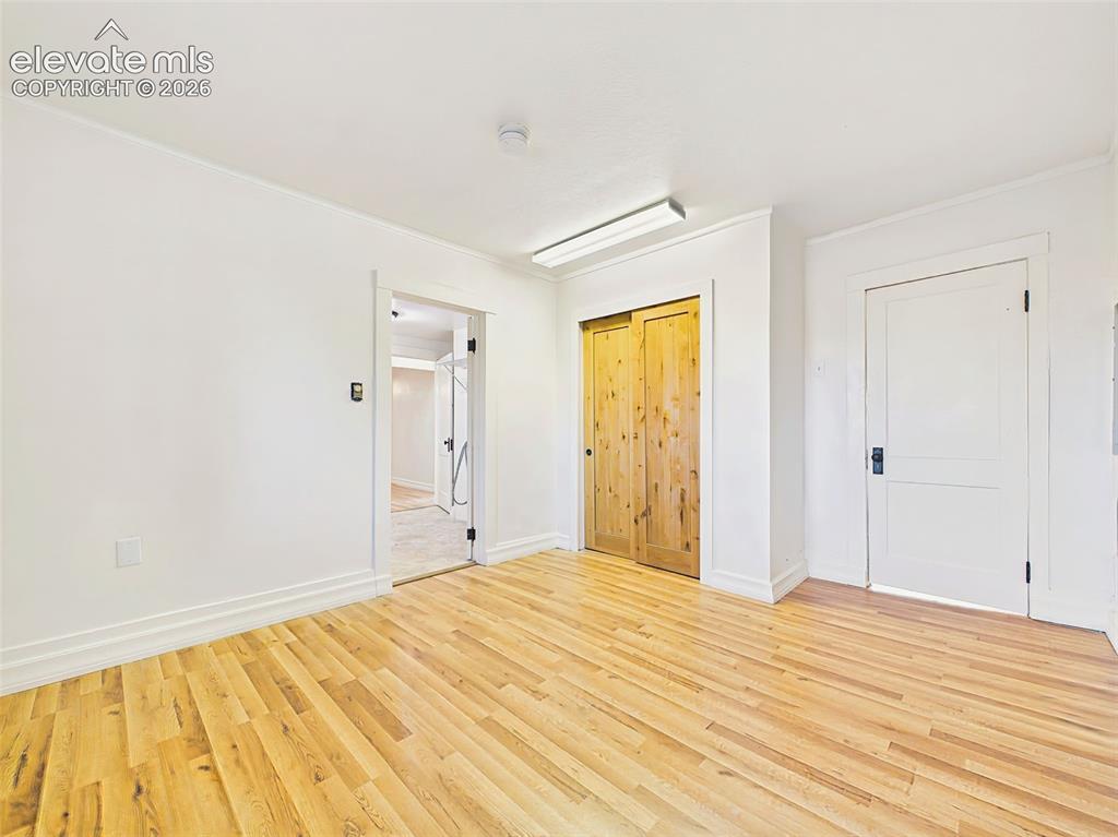 Image 29 of 50: Primary Bedroom – Bright primary bedroom showcases floors, rustic sliding c