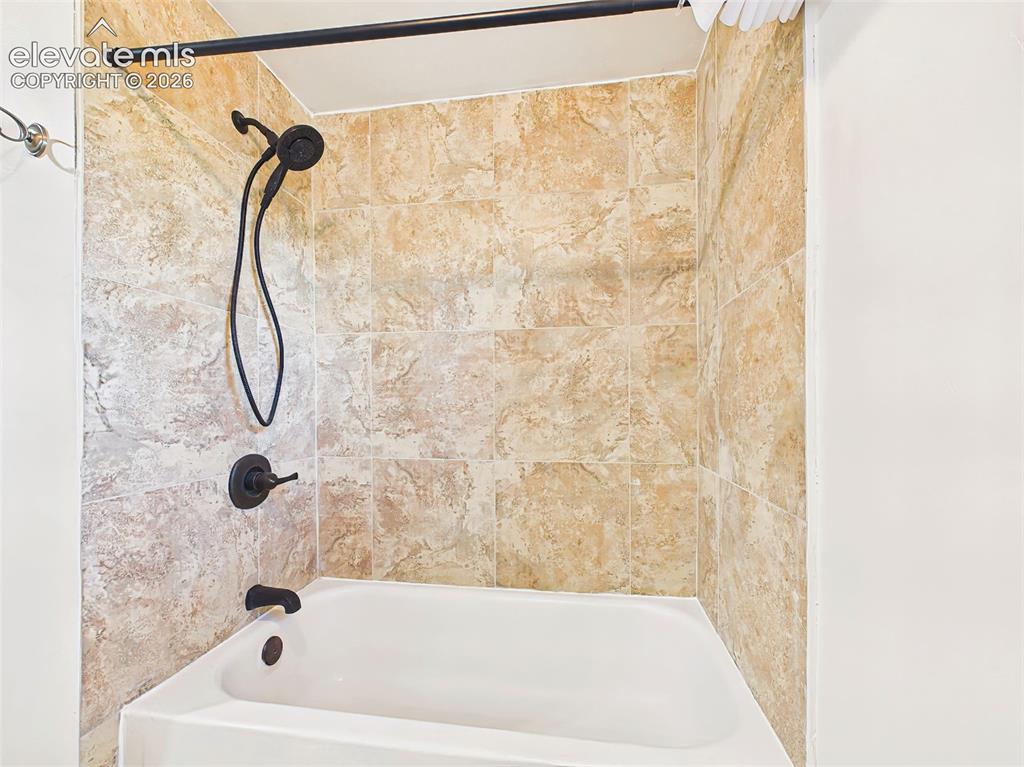 Image 35 of 50: Bathroom – Updated full bathroom features a tiled tub and shower surround w