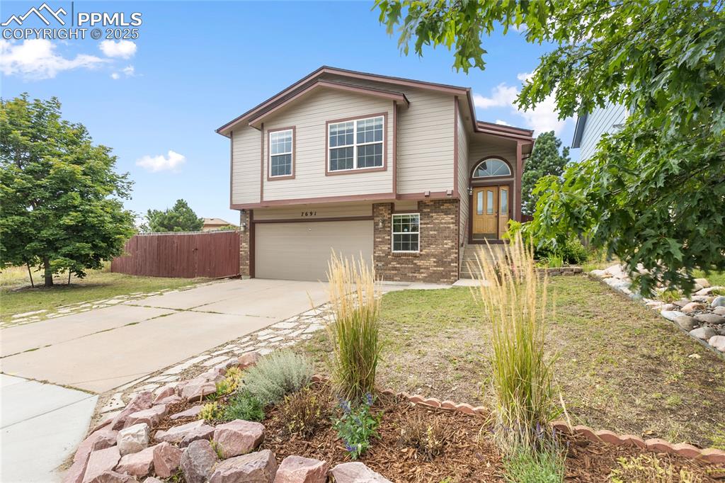Caption: Traditional home with a brick façade accented by wood siding, a concrete driveway, and an attached g