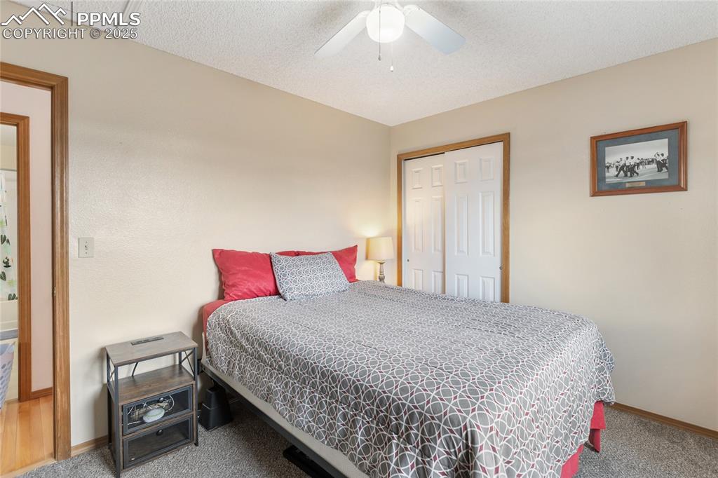Image 13 of 28: Bedroom featuring a closet, a textured ceiling, carpet, and a ceiling fan