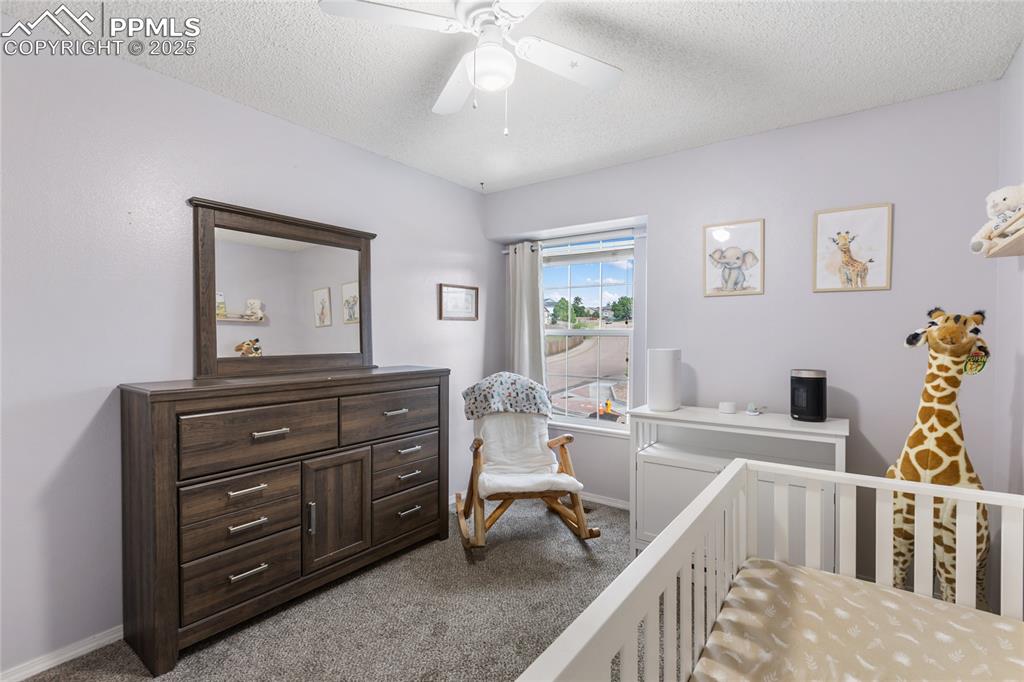 Image 15 of 28: Bedroom with dark carpet, a textured ceiling, and a ceiling fan 