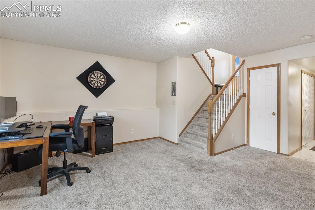Image 18 of 28: Office area with light carpet and a textured ceiling