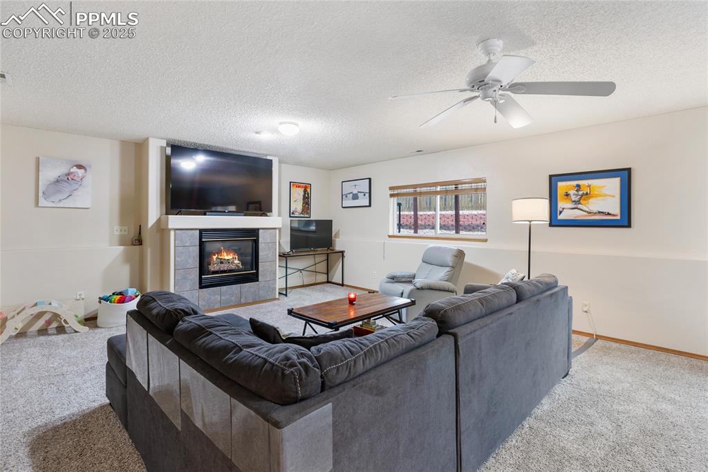 Image 2 of 28: Carpeted living room featuring a textured ceiling, a tile fireplace, and a 