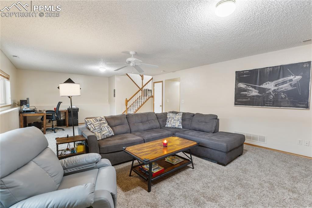 Image 20 of 28: Living room with an office area, a ceiling fan, carpet flooring, a textured