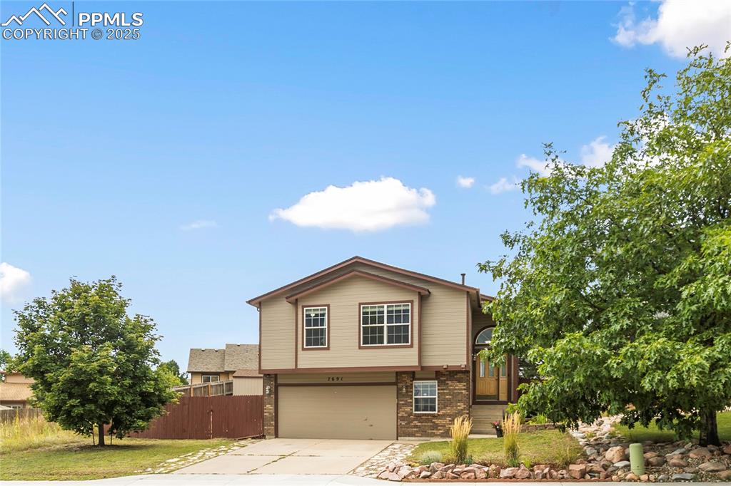 Image 24 of 28: View of front of property with driveway, brick siding, and an attached gara