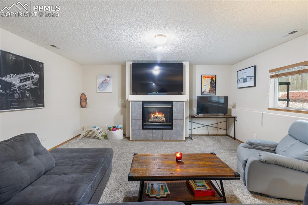 Image 3 of 28: Carpeted living room featuring a tile fireplace and a textured ceiling