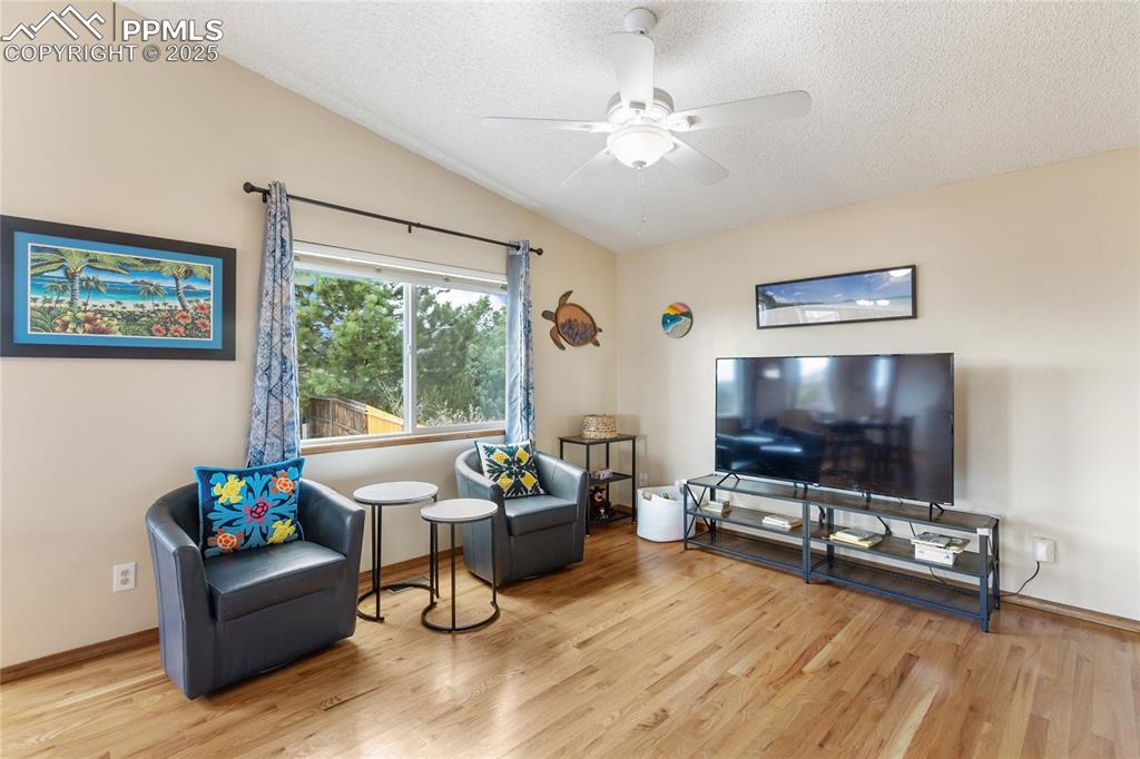 Image 6 of 28: Living area with vaulted ceiling, light wood-type flooring, a textured ceil